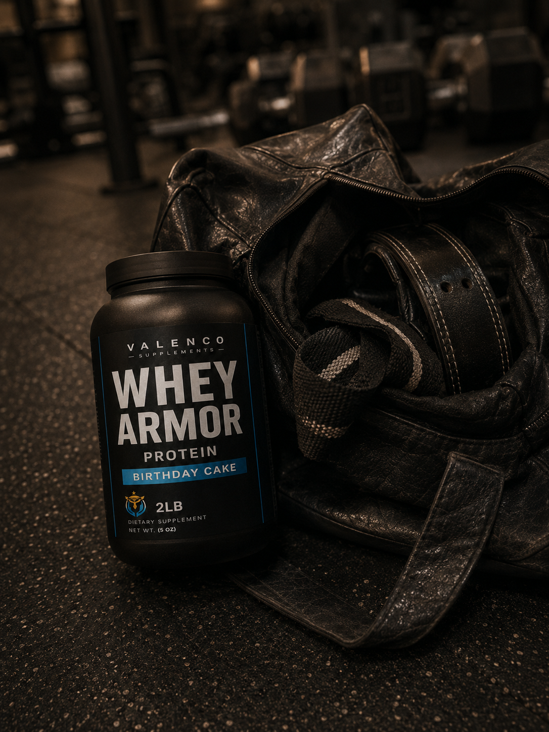 Valenco Whey Armor on a gym bag beside dumbbells, dim warm gym lighting